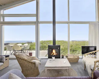 Brændeovn i sommerhus med udsigt ud over havet og klitter