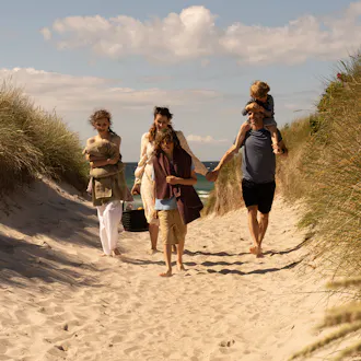Familie på tur fra stranden og hjem til sommerhuset. Finkornet sand, marehalm og klitlandskab.
